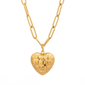Gros plan d'un pendentif cœur doré avec une texture tissée sur un fond blanc neutre