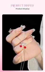 Dettaglio della collana a ciliegia con perle rosse e fiocco di strass su catena d'argento