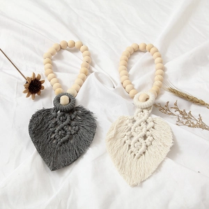 Close-up of hand-woven leaf-shaped cotton curtain tiebacks with natural wooden beads