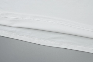 Gros plan des coutures soignées et du tissu en coton blanc sur l'ourlet de la robe d'été
