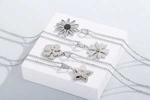Detail shot of four stainless steel necklaces with daisy, cloud, and star pendants