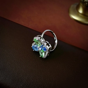 Macro shot of silver flower ring with blue and green stones on leather background