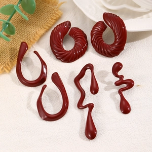 Detail of vintage burgundy resin earrings with spiral textures and sleek geometric shapes