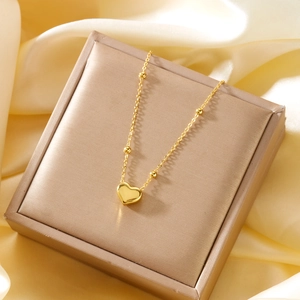 Close-up of heart pendant necklace with gold beads on luxurious silk background