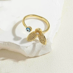 Macro shot of gold evil eye flower ring with sparkling crystals on white stone surface