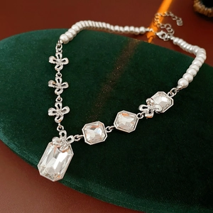 Detail of beaded pearl necklace with floral metal chain and large clear faceted gems