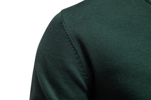 Macro shot of dark green knit sweater shoulder seam showing fine fabric texture