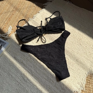 Detail of black textured bikini fabric with tie-up front and high-cut bottoms