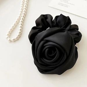 Detail of a black satin rose hair scrunchie with elegant silk texture and pearl accents