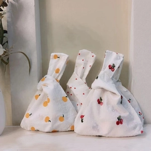 Japanese knot wrist bags with orange, heart, and cherry patterns on textured cotton