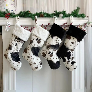 Detailed view of four plush cow print Christmas stockings hanging on a white fireplace mantle