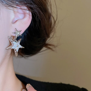 Close-up of double star drop earrings with sparkling pavé stones on silver finish
