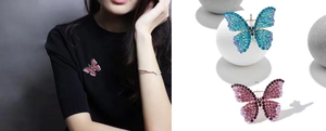 Detail view of sparkling crystal butterfly brooches in blue and pink on clothing