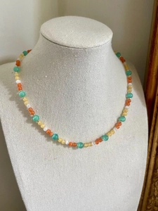 Detail of colorful cat eye stone beaded necklace with pastel mint green and orange pearls