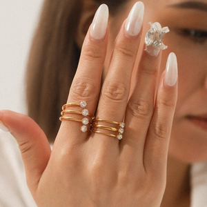 Nahaufnahme von dreischichtigen Gold-Edelstahlringen mit Zirkonsteinen an der Hand