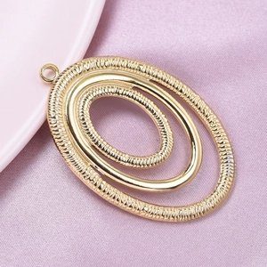 Detailed macro view of a gold oval layered pendant with textured finish on pink silk