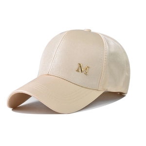 Dettaglio del cappellino beige con corona in raso e logo M in metallo dorato