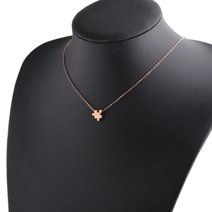 Macro detail of rose gold puzzle piece pendant on black mannequin with polished finish