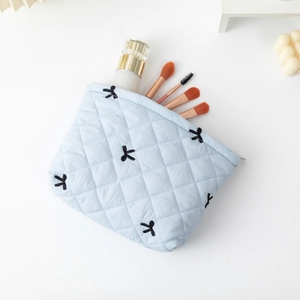 Light blue quilted cosmetic bag with black bow embroidery and zipper closure