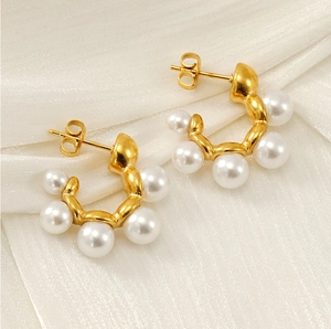 Detailed close-up of French vintage C-shape gold earrings with white inlaid pearls
