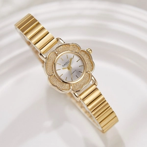Montre vintage dorée pour femme au cadran floral posée sur une assiette en céramique