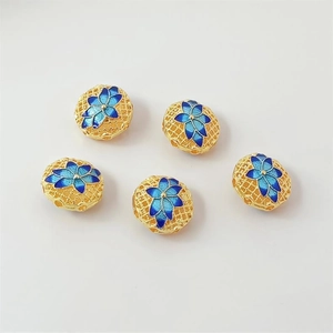 Macro shot of 18K gold-plated cloisonne watermelon beads with blue floral enamel detail
