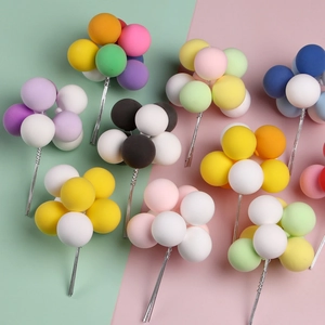 Colorful clay balloon cake toppers on a vibrant pink and green background for parties