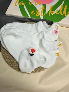Close-up of white mesh socks featuring colorful tulip and crown embroidery details