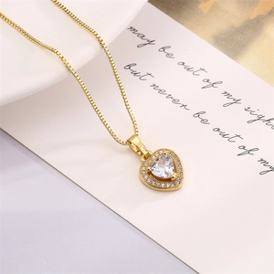 Macro detail of gold heart pendant necklace featuring micro-pave cubic zirconia on white card