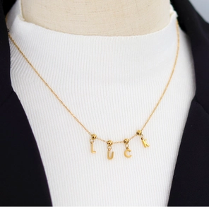 Detailed view of gold LUCK letter pendant necklace on a professional mannequin model