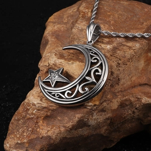 Pendentif étoile et lune en acier titane avec cristal sur roche rustique