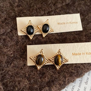 Detailed close-up of vintage gold geometric earrings with tiger eye and black gemstones