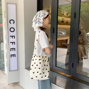 Detail of canvas shoulder bag with heart pattern and red decorative label on the front