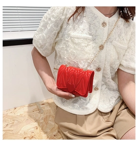Detail of red quilted heart purse with gold metal chain strap on a white lace top
