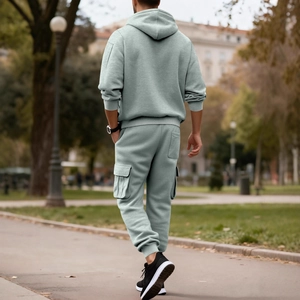 Men's sage green hoodie and cargo joggers set shown in a stylish outdoor back view