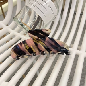 Close-up of a large floral marble acetate hair claw clip with colorful pink and gold swirls
