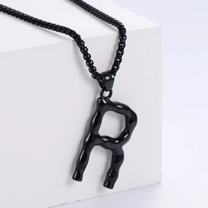 Gros plan du pendentif lettre R en métal liquide noir avec une chaîne à billes assortie