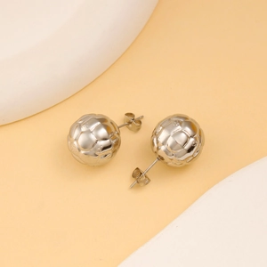 Detail shot of silver textured sphere earrings with soccer-like patterns and metal backings
