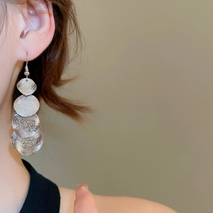 Detail of silver matte metal tiered disc earrings shown on a model for a chic look