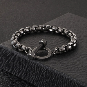 Détail du bracelet industriel en acier vintage avec fermoir barre T sur boîte noire