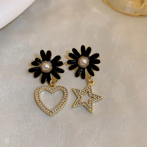 Detail of vintage black daisy earrings with pearl center and rhinestone heart star charms
