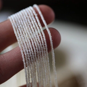 Tiny natural white freshwater pearls held on fingertips for DIY jewelry making material