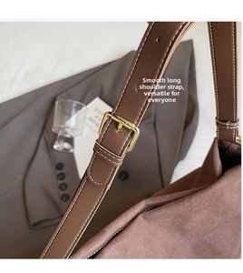Detail of suede shoulder bag strap with white contrast stitching and gold buckle