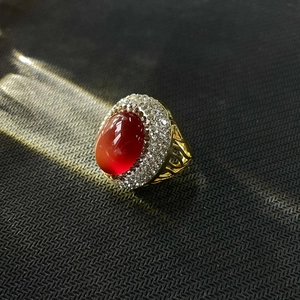Détail macro de bague vintage en or avec pierre rouge et gravure florale ajourée