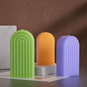 Velas aromáticas con arco de rayas en verde, naranja y violeta sobre bloques de piedra