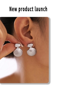 Detailed view of silver scallop-shaped geometric earrings on a model's ear lobe