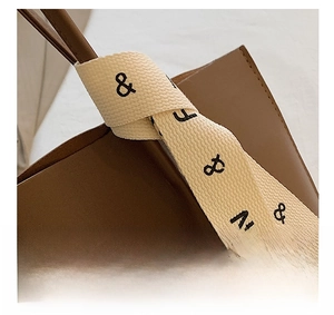 Detail of brown leather tote handle with beige canvas strap and fashion typography