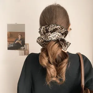 Detail of leopard print scrunchie with black hem on a woman's low ponytail style
