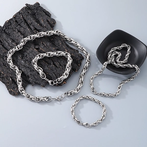 Detail of silver twisted rope chain necklaces and bracelets on dark textured bark