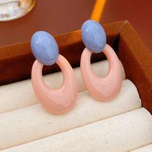 Close-up of geometric oval earrings in blue and peach resin displayed in a luxury jewelry box